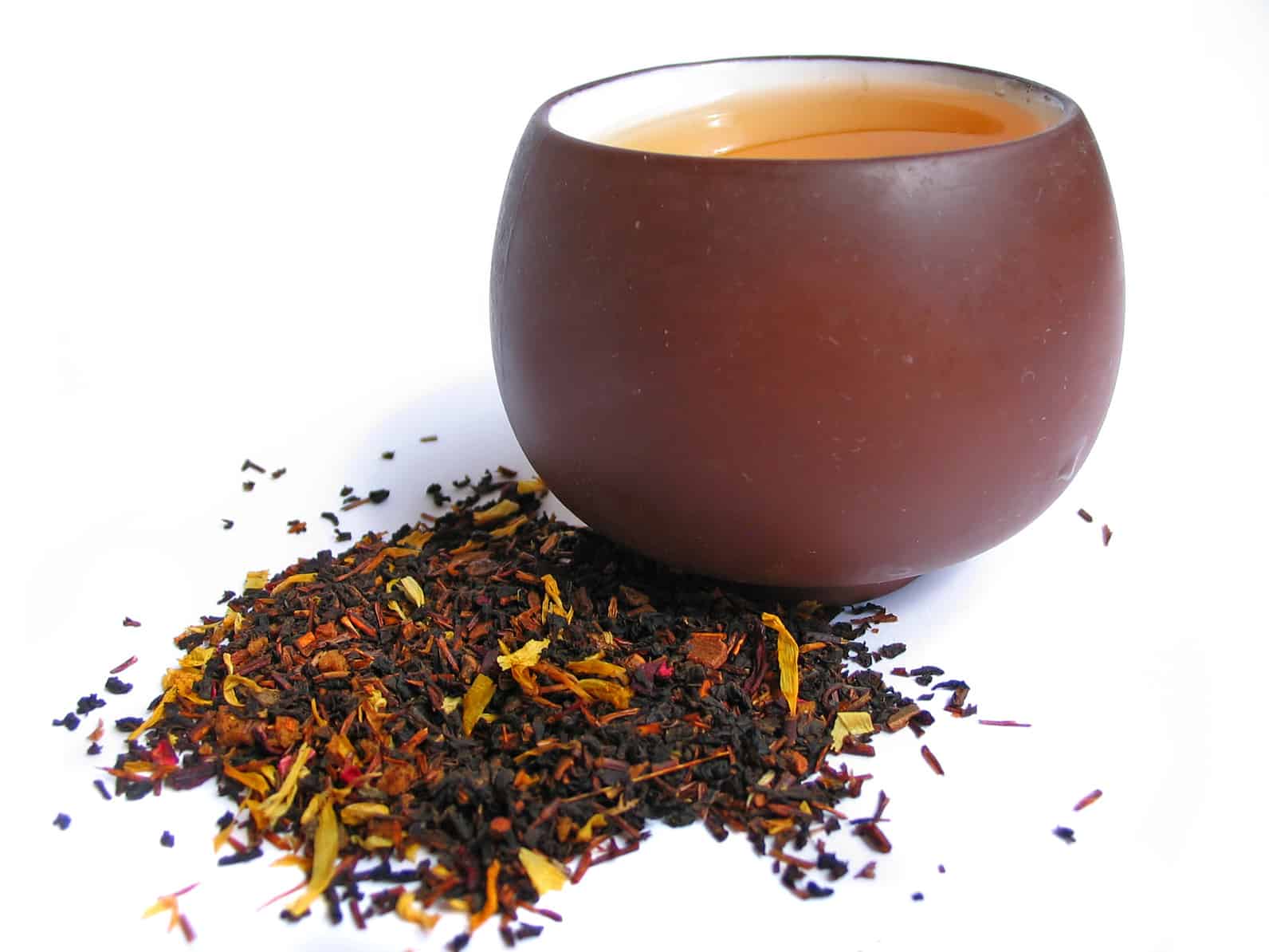 Un mélange de feuilles de thé noir et fleur avec une tasse de thé