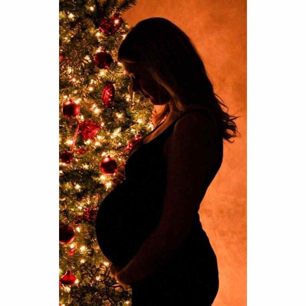 Fille enceinte à Noël pose devant son sapin de Noël